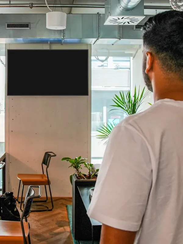 Representative photo: a man looking at a wall screen in a coworking space