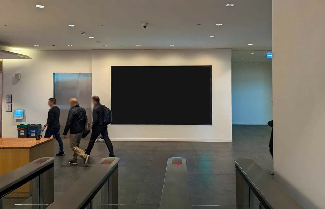 A large screen in an office lobby, behind the entrance gates